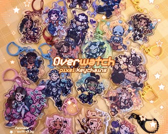 May include: A collection of Overwatch pixel keychains featuring various characters. The keychains are clear with colorful character designs and attached key rings. The text "Overwatch pixel Keychains" is visible.