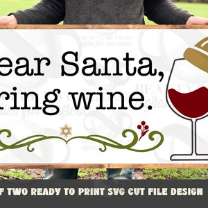 May include: A white wooden sign with the text "Dear Santa, Bring wine." in black lettering. A red wine glass with a gold Santa hat on top is on the right side of the sign.