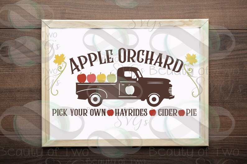 May include: A white sign with brown lettering that reads "APPLE ORCHARD" with a silhouette of a brown pickup truck with red apples in the bed. The text below the truck reads "PICK YOUR OWN HAYRIDES CIDER PIE".