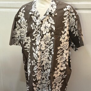 May include: A brown short-sleeved button-up shirt with a white floral print. The shirt has a classic collar and a button-up front.