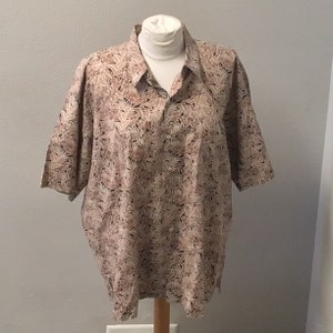 May include: A beige short-sleeved button-down shirt with a brown and white floral pattern.