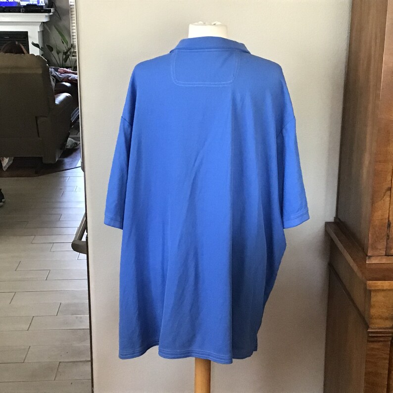 May include: A solid blue short-sleeved polo shirt with a white collar and a single button closure.