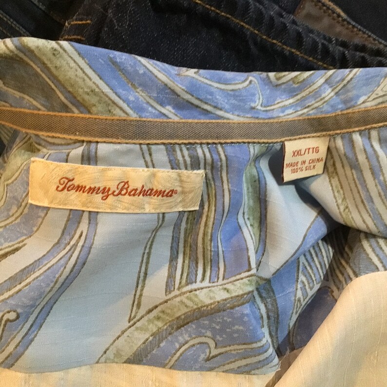 May include: A Tommy Bahama brand shirt with a blue and green patterned design. The tag says "XXL/TTG Made in China 100% Silk"
