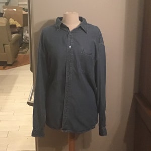 May include: A dark blue denim long-sleeve shirt with a button-down front and a single chest pocket.