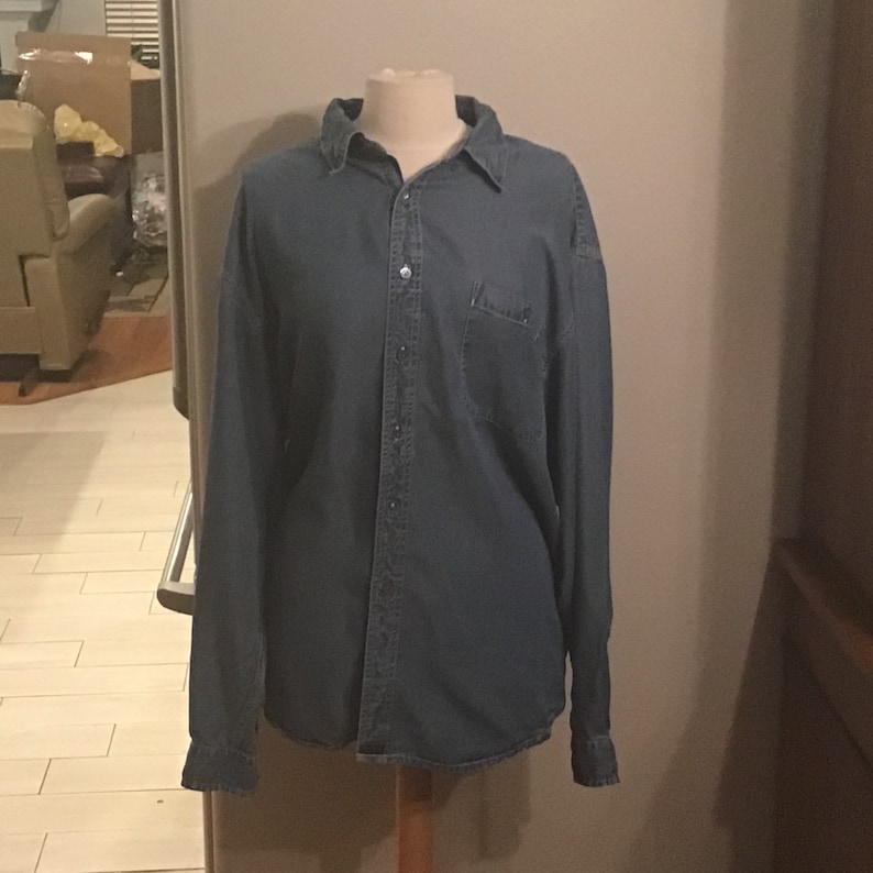 May include: A dark blue denim long-sleeve shirt with a button-down front and a single chest pocket.
