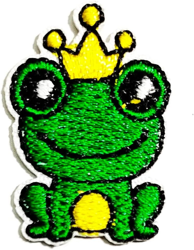 May include: A green frog wearing a yellow crown. The frog has big eyes and a smiling mouth. The frog is sitting on its bottom with its legs tucked in.