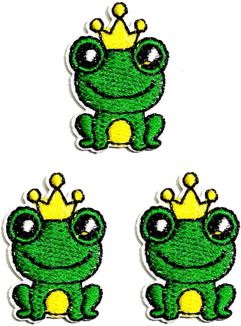 May include: Three green frog iron-on patches with yellow crowns. Each frog is sitting with a big smile and large eyes.