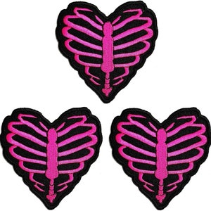 Könnte beinhalten: Drei herzförmige Patches in Pink und Schwarz mit einem Rippenknochen-Design.