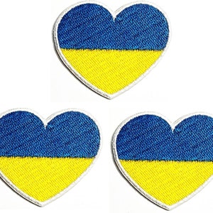 Puede incluir: Tres parches bordados en forma de corazón con los colores de la bandera de Ucrania: azul y amarillo.