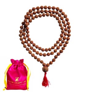 May include: A three-strand Rudraksha bead necklace with a red tassel, displayed with a pink satin drawstring bag. The beads are brown and strung on a red cord. The bag has yellow drawstrings and the text "Zillion Craft - Himalayan natural Rudraksha".