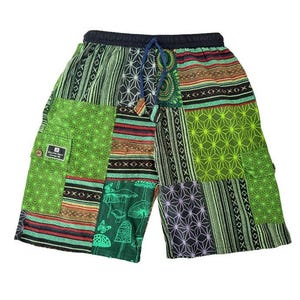 Peut inclure: Shorts patchwork aux tons de vert, marron et noir, avec une taille élastique et un cordon de serrage. Les motifs géométriques et inspirés de la nature, tels que des étoiles, des rayures et des champignons, ornent le tissu. Une petite poche avec un bouton est visible.