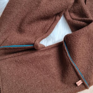 May include: Brown fleece pants with a teal blue trim and a small brown label that says "VIBHA" on the side.