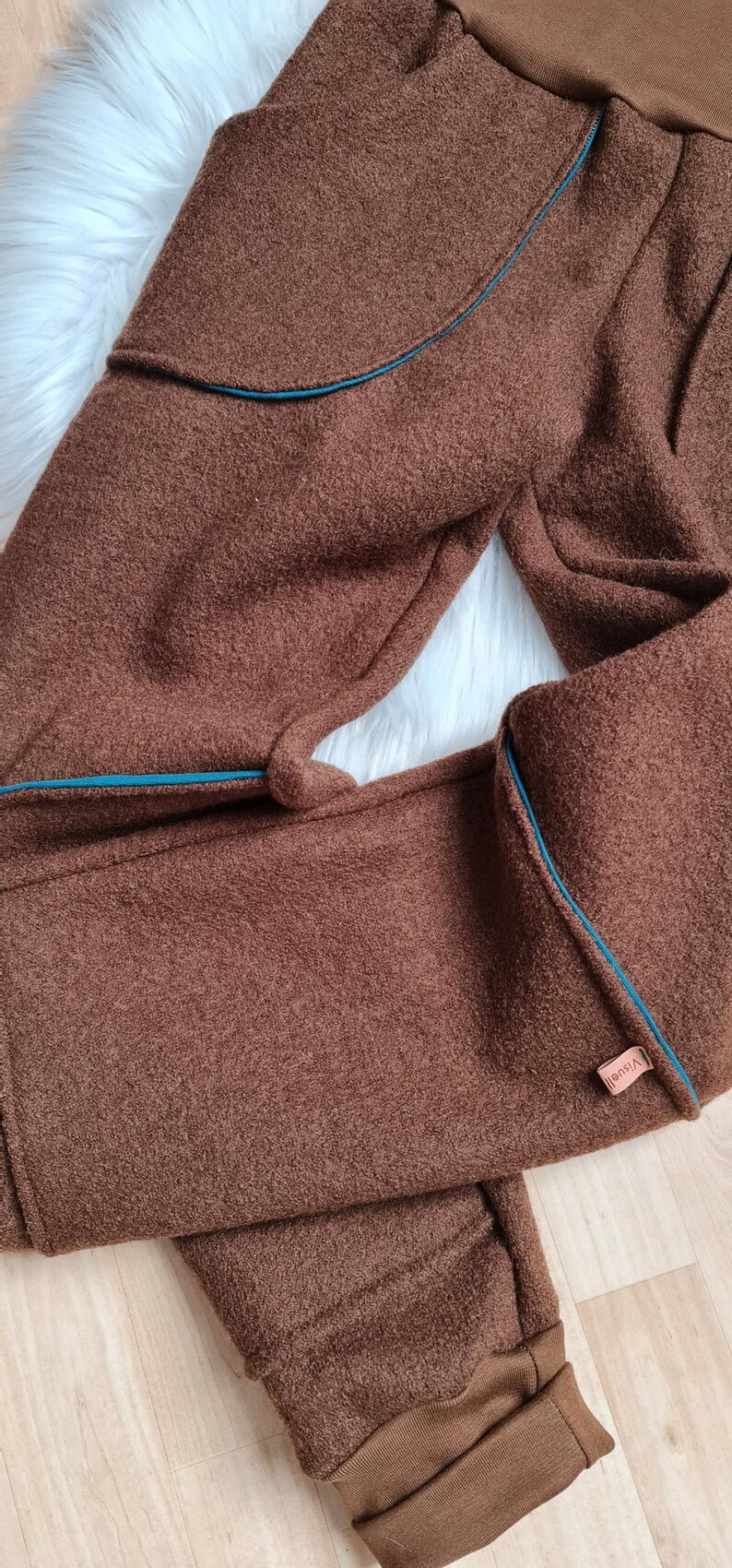 May include: Brown fleece pants with a teal blue trim and a small brown label that says "VIBHA" on the side.
