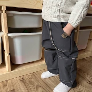 Op de afbeelding: Grijze broek met ritszakken en witte stiksels. De broek heeft een ontspannen pasvorm en is gemaakt van een zachte, comfortabele stof.