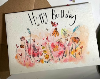 以下が含まれることがあります： 水彩画のグリーティングカードで、花柄のデザインと「Happy Birthday」の文字が書かれています。カードは、ピンク、オレンジ、黄色の花と葉が描かれた水彩画の背景になっています。