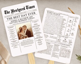 Könnte beinhalten: Zwei weiße Hochzeitsfächer mit Holzgriffen, die wie Zeitungen gestaltet sind. Die Schlagzeile lautet "The Newlywed Times" und "The Best Day Ever". Ein Fächer zeigt ein Foto eines Paares, der andere ein Wortsuchrätsel. Ein beiges Band, ein Tannenzapfen und Grünzeug sind ebenfalls vorhanden.