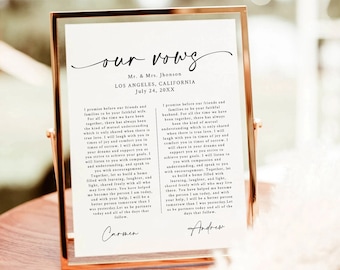 May include: A framed wedding vow print with the text "our vows" in cursive script. The vows are written in black ink on white paper. The print is framed in a gold frame and is sitting on a wooden table. The text includes the names Carmen and Andrew.