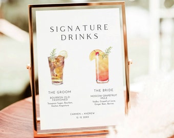 May include: A framed sign with the text "SIGNATURE DRINKS" and two watercolor cocktail illustrations. The sign lists "BOURBON OLD FASHIONED" and "MOSCOW GRAPEFRUIT MULE" with ingredients. The names "CARMEN + ANDREW" and a date are also included.