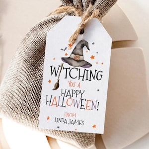 Op de afbeelding: Een kleine jute cadeauzak met een label met de tekst "Witching You a Happy Halloween!". Het label toont een heksenhoed, sterren en een bezemillustratie. Het label bevat ook de naam "Linda James".