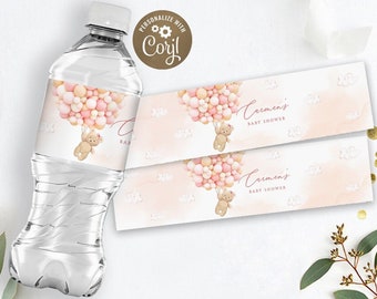 May include: Water bottle label with a pink and gold balloon design. A teddy bear is holding the balloons. The text on the label says "Carmen's Baby Shower".