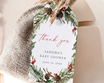Op de afbeelding: Een kleine jute cadeauzak met een label met de tekst "Bedankt" voor Sandra's babyshower. Het label is versierd met een aquarelkrans van dennennaalden, dennenappels en rode bessen. De datum van de babyshower is 24 juni 20XX.