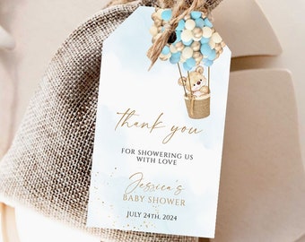 May include: A blue and gold thank you tag with a teddy bear in a hot air balloon. The tag says "Thank you for showering us with love, Jessica's Baby Shower, July 24th, 2024".