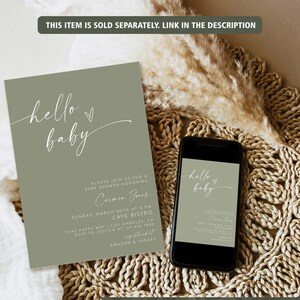 May include: A green and white baby shower invitation with the text "hello baby" in a script font. The invitation includes details for a baby shower honoring Carmen Jones, including the date, time, location, and RSVP information. The invitation also includes the text "registered at Amazon & Target".