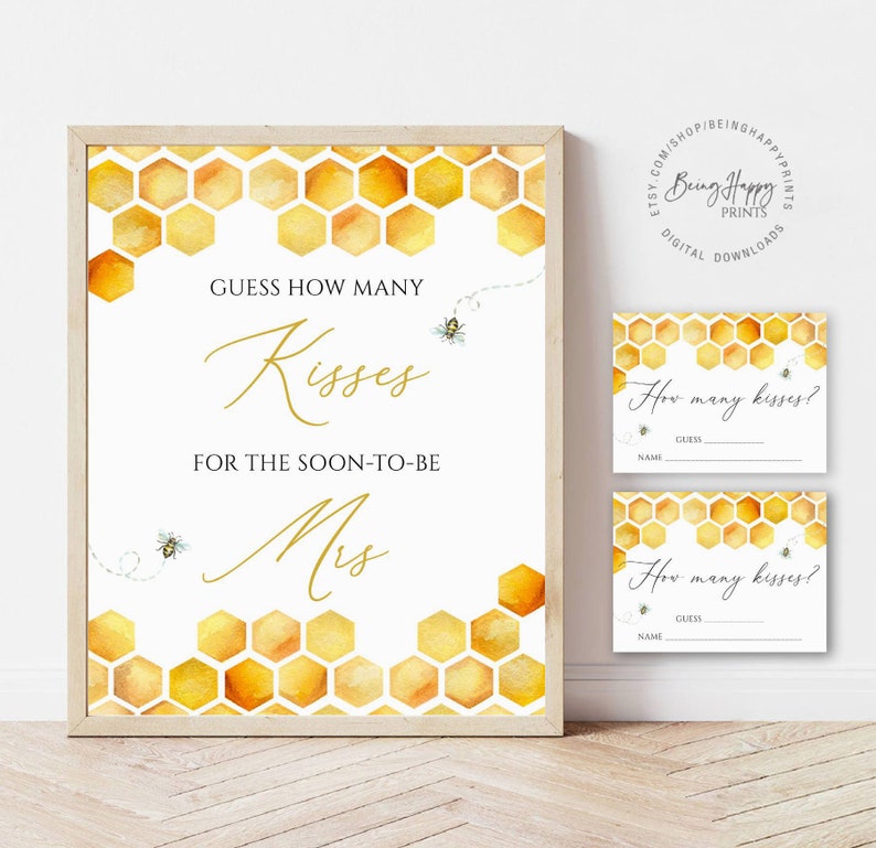 May include: A framed sign and two smaller cards with a bee-themed design. The sign reads "Guess How Many Kisses For The Soon-To-Be Mrs." in gold script. The background features a honeycomb pattern.