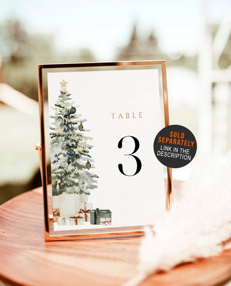 May include: A framed table number 3 with a watercolor Christmas tree illustration. The tree is decorated with ornaments and a star. The words "TABLE" and the number "3" are displayed in elegant fonts. A sticker says "SOLD SEPARATELY".