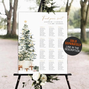 May include: A wedding seating chart featuring a watercolor Christmas tree design. The sign includes the names Andrew and Carmen, the date, and the location. The sign is displayed on a black easel with floral accents. Text on the sign reads "Find your seat".