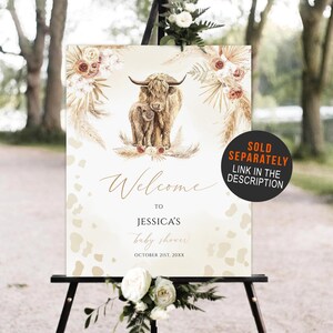 May include: Welcome to Jessica's baby shower sign with a watercolor illustration of a Highland cow and calf with floral accents. The sign is decorated with a beige and brown animal print pattern. The text on the sign reads "Welcome to Jessica's baby shower October 21st, 20XX".