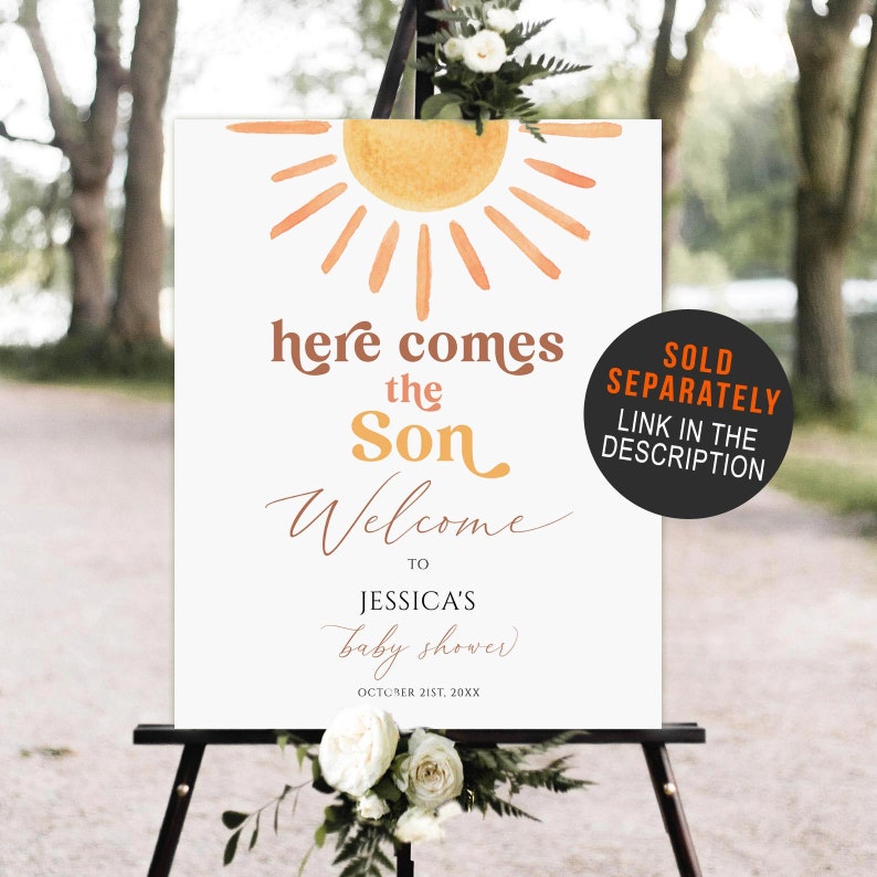 以下が含まれることがあります： 水彩画の太陽の絵と「here comes the son welcome to Jessica's baby shower October 21st, 20XX」という文字が書かれた白いウェルカムサイン。サインは木製のイーゼルの上に置かれています。