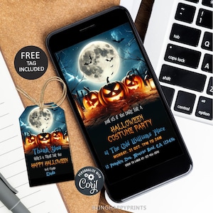 Op de afbeelding: Een smartphone toont een uitnodiging voor een Halloween-kostuumfeest met pompoenen onder een volle maan. Een bijpassend label met de tekst "Bedankt" en "Gelukkig Halloween" is inbegrepen. Het label is vastgebonden met touw.