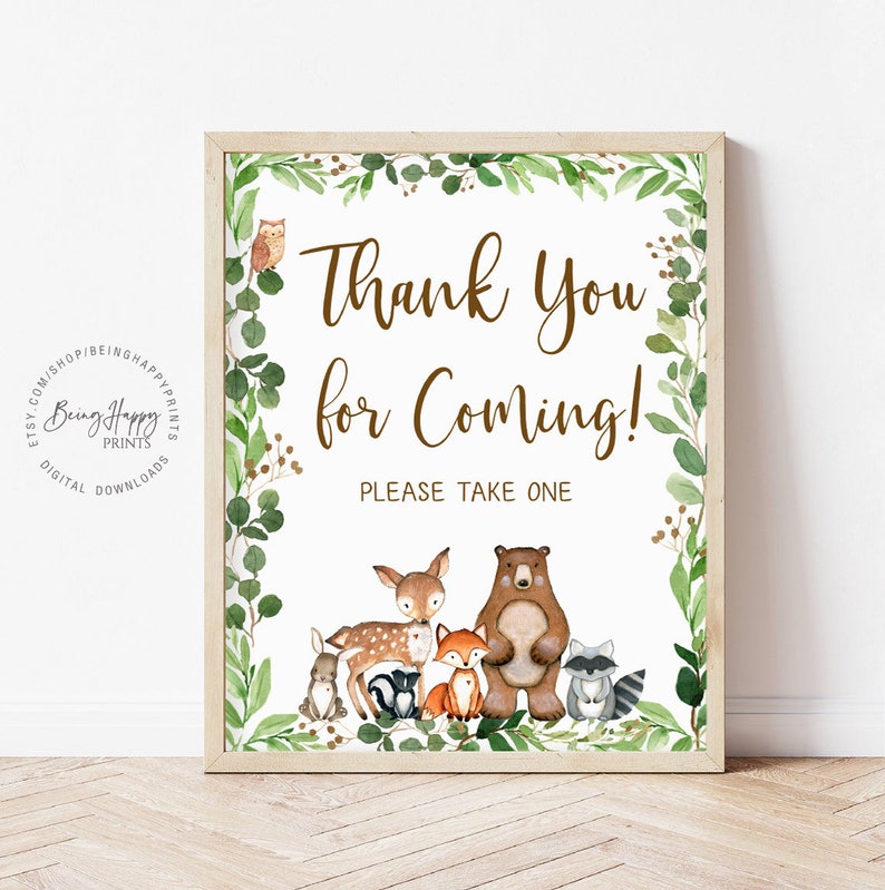 May include: A white sign with a brown wooden frame and green foliage border. The sign says "Thank You for Coming!" and "Please Take One". There are cartoon woodland animals including a deer, bear, fox, rabbit, raccoon, and squirrel.