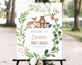 Op de afbeelding: Welkom op Carmen's Baby Shower bord met een aquarelkrans van groene bladeren en takken. De krans omringt een groep bosdieren, waaronder een hert, een vos, een beer, een wasbeer en een uil. De tekst luidt "Welkom op Carmen's Baby Shower 21 oktober 20XX".