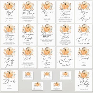 May include: A collection of twenty-five white rectangular baby shower signs and cards featuring watercolor pumpkin and floral illustrations. Each piece displays black text with various game titles and instructions, including Thank You, Diaper Raffle, and Guess How Many.