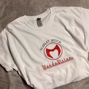 May include: White t-shirt with a red embroidered logo that says "Scarlet Witch" and "WandaVision".