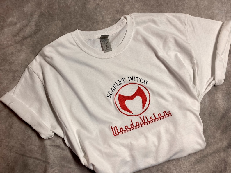 May include: White t-shirt with a red embroidered logo that says "Scarlet Witch" and "WandaVision".