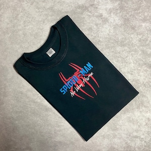 以下が含まれることがあります： 赤い糸と青い糸で刺繍されたスパイダーマンのロゴと「ノー・ウェイ・ホーム」の文字が書かれた黒いTシャツ。
