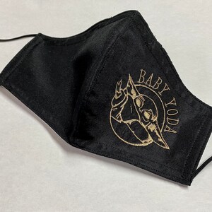 May include: Black face mask with a gold embroidered image of Baby Yoda and the text "Baby Yoda".