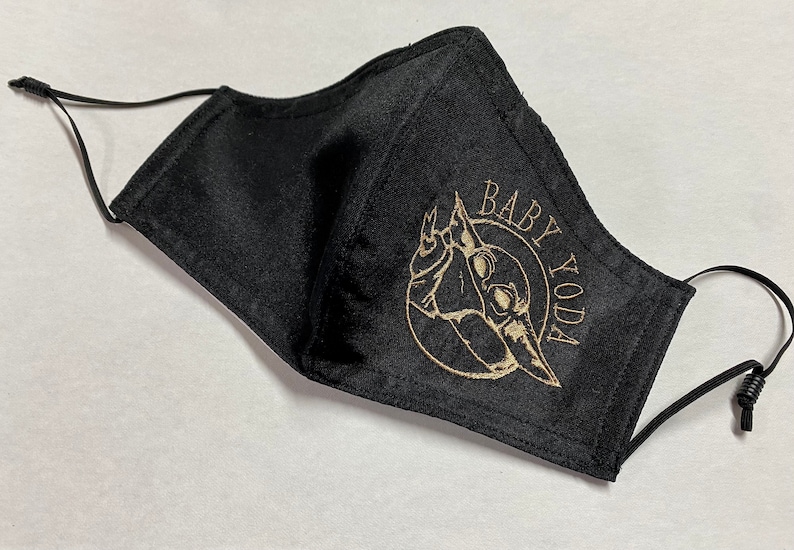 May include: Black face mask with a gold embroidered image of Baby Yoda and the text "Baby Yoda".