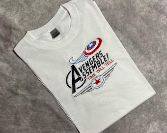 May include: White t-shirt featuring a graphic of Captain America's shield and the text "Avengers Assemble! Time Will Tell".