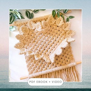 以下が含まれることがあります： 正方形の中央と結び目のフリンジの装飾的な縁取りを持つ、ベージュの糸で編まれた壁掛け。下部に長いフリンジが付いています。壁掛けの下に「PDF EBOOK + VIDEO」というテキストが印刷されています。