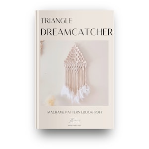 Pode incluir: Um ebook para download digital para um padrão de apanhador de sonhos triangular de macramé. A capa apresenta um apanhador de sonhos de macramé branco com penas penduradas na parte inferior. O título do ebook é "Triangle Dreamcatcher" e o texto "Macrame Pattern Ebook (PDF)" está abaixo da imagem.