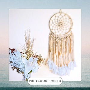 May include: A cream-colored macrame dreamcatcher with a circular woven design and hanging tassels. White feathers adorn the bottom. A bouquet of white and brown flowers sits to the left. The text "PDF EBOOK + VIDEO" is at the bottom.