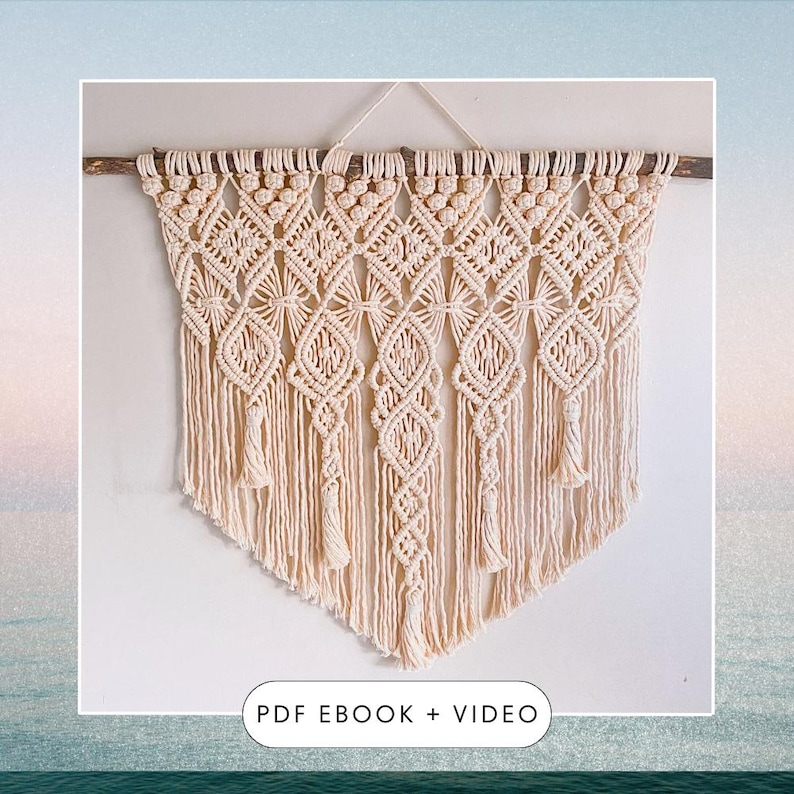 Pu&ograve; includere: Un arazzo da parete in macram&egrave; beige con un'asta di legno nella parte superiore e frange nella parte inferiore. L'arazzo presenta un motivo geometrico con forme a diamante e un design a stella ripetuto. Il testo "PDF EBOOK + VIDEO" &egrave; stampato sotto l'arazzo.