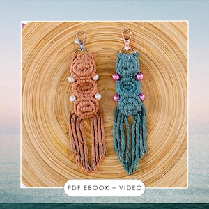 May include: Two macrame keychains, one peach, one teal. The peach keychain has white beads, the teal one has pink beads. Both have metal clasps and a fringe of knotted threads. They are displayed on a wooden surface.