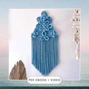 Puede incluir: Un tapiz de macramé azul con forma triangular y flecos. El tapiz tiene un patrón complejo de nudos y bucles. El texto "PDF EBOOK + VIDEO" está en la parte inferior de la imagen.
