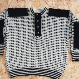 May include: A white and black patterned sweater with black elbow patches and a button-up collar.