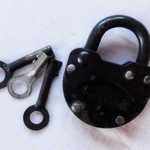 Puede incluir: Un candado negro con un acabado metálico brillante y tres llaves. El candado tiene un arco en forma de D y una cerradura en el lateral.